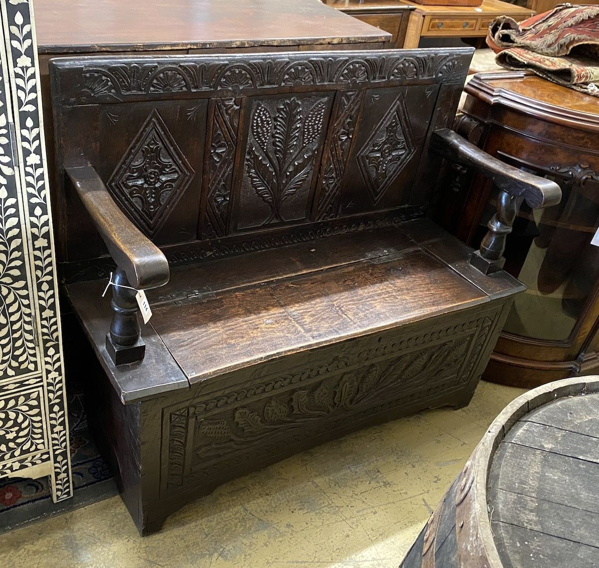 An 18th century carved oak box seat settle incorporating old timber, length 120cm, depth 44cm, height 101cm